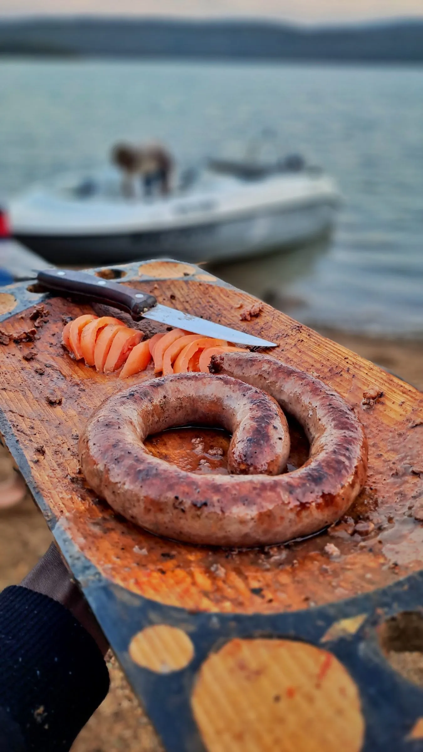 Boerewors on a wooden board with the boat in the background