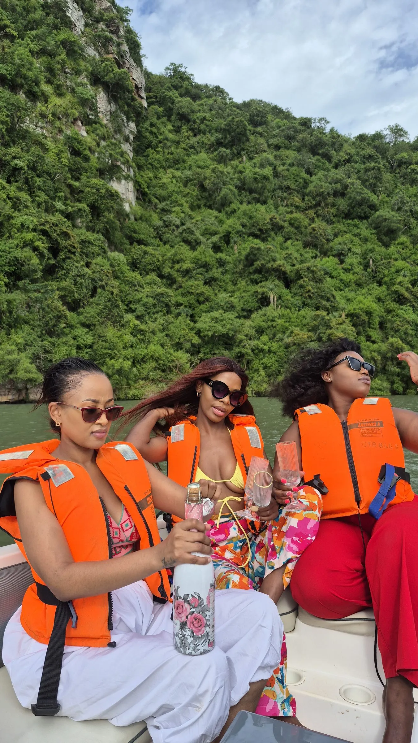 Guests in orange life jackets toasting with bubbly on the boat